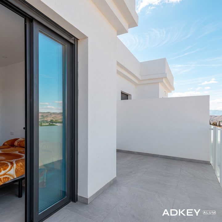 Baie coulissante en aluminium anthracite avec coffre tunnel intégré, ouvrant sur un balcon de villa à Cap Spartel — réalisation AdKey Aluminium