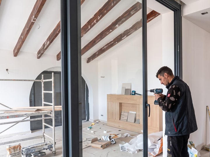 Technicien AdKey Aluminium en cours d'installation d'une baie coulissante en aluminium anthracite dans une villa en chantier