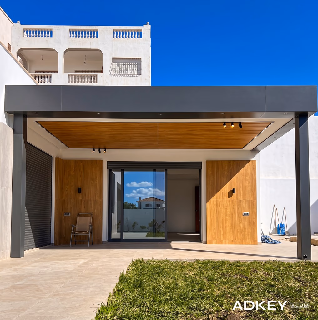 Pergola adossée à toiture plate en aluminium anthracite couvrant la terrasse d'une villa moderne avec baie coulissante à Tanger — Aluminium Tanger